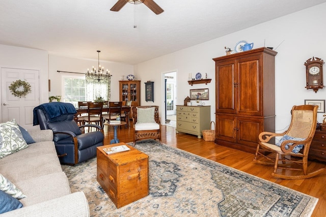 living area featuring light wood-style floors and ceiling fan with notable chandelier