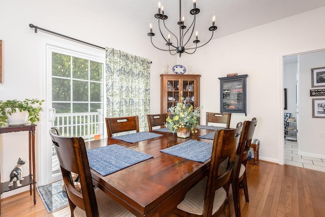 dining space with baseboards, light wood-type flooring, and a chandelier