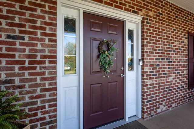 property entrance featuring a porch and brick siding