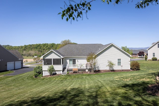 back of property featuring a lawn, a garage, and a sunroom