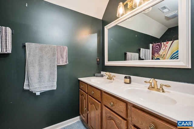 full bath featuring visible vents, a sink, vaulted ceiling, and double vanity