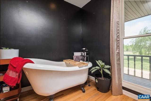 bathroom with baseboards, a freestanding bath, and wood finished floors