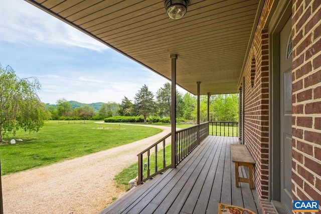 deck featuring covered porch, a lawn, and a mountain view