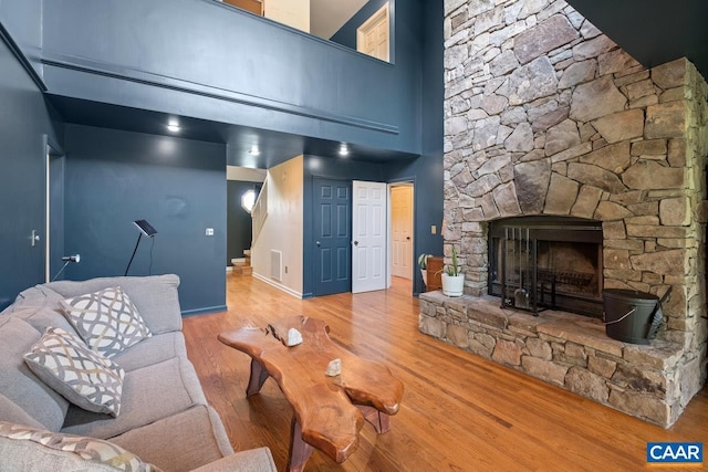 living area featuring visible vents, stairs, wood finished floors, a fireplace, and baseboards