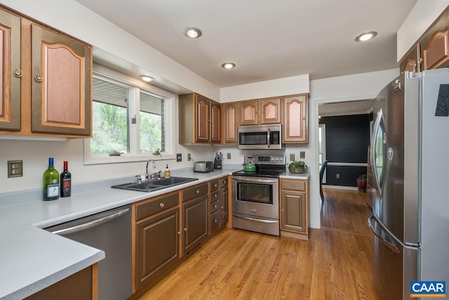 kitchen featuring light countertops, a sink, light wood-type flooring, and stainless steel appliances
