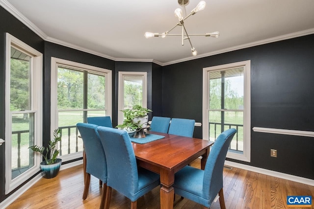 dining space with baseboards, ornamental molding, light wood-type flooring, and a notable chandelier