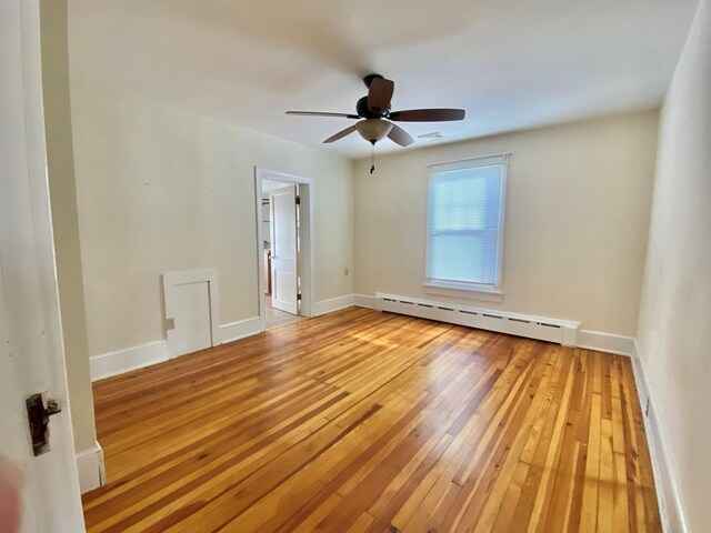 spare room featuring light wood-type flooring, a baseboard radiator, ceiling fan, and baseboards