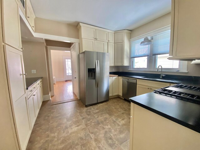 kitchen featuring cream cabinets, a wealth of natural light, stainless steel appliances, and sink