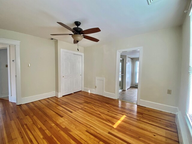 empty room featuring light wood finished floors, baseboards, visible vents, and ceiling fan