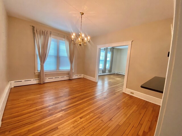 unfurnished dining area featuring hardwood / wood-style flooring, baseboards, and a chandelier