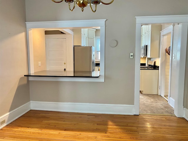 unfurnished dining area featuring light hardwood / wood-style flooring and a notable chandelier