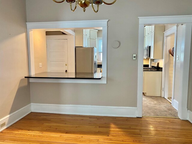 interior space with a chandelier, baseboards, and hardwood / wood-style floors