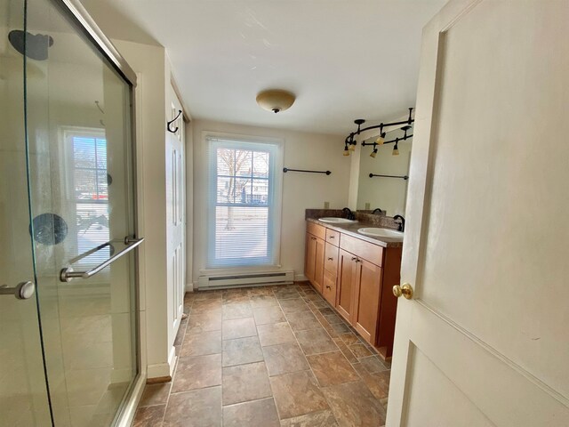 bathroom featuring a baseboard heating unit, a stall shower, a sink, and double vanity