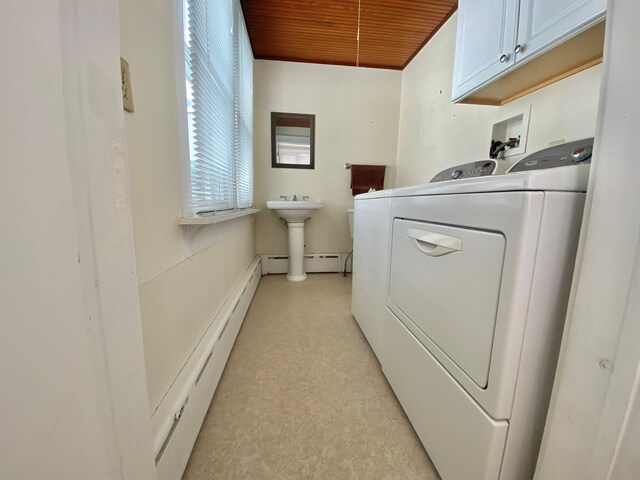 laundry area with light floors, baseboard heating, washing machine and dryer, and cabinet space