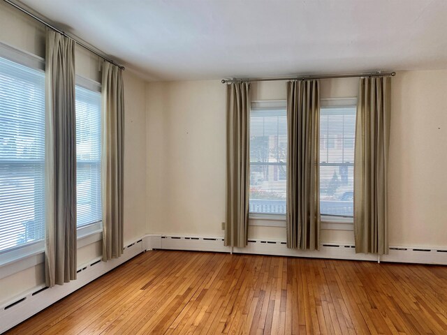 empty room with light wood finished floors and baseboard heating