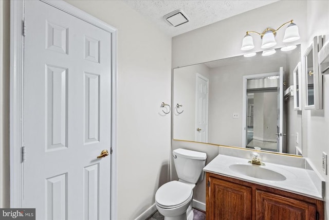 bathroom with vanity, toilet, a textured ceiling, and visible vents