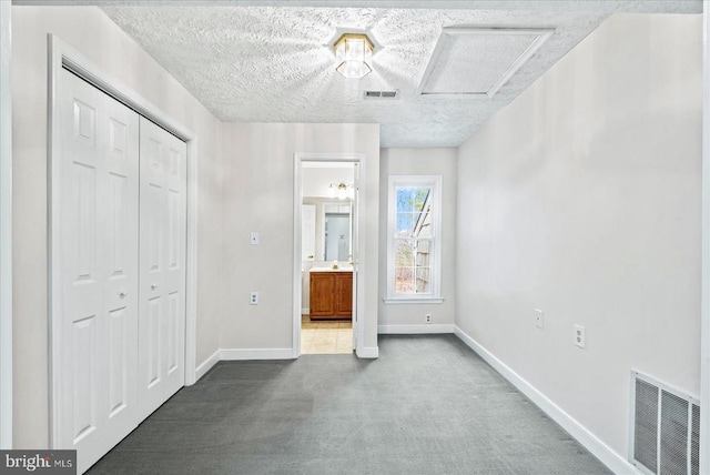 unfurnished bedroom with baseboards, attic access, carpet floors, and visible vents