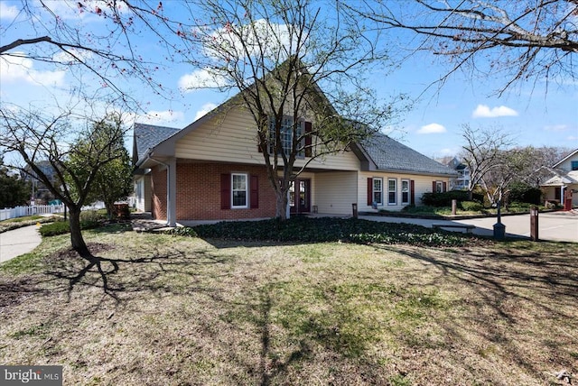 view of front of home with brick siding, fence, and a front yard