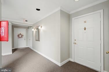 foyer with crown molding, baseboards, and dark carpet