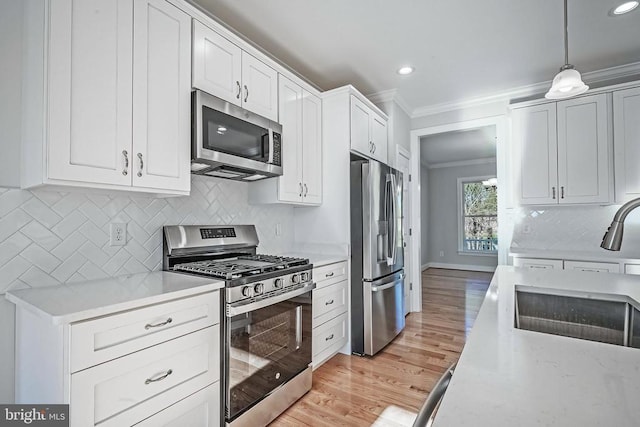 kitchen with appliances with stainless steel finishes, pendant lighting, white cabinetry, decorative backsplash, and ornamental molding