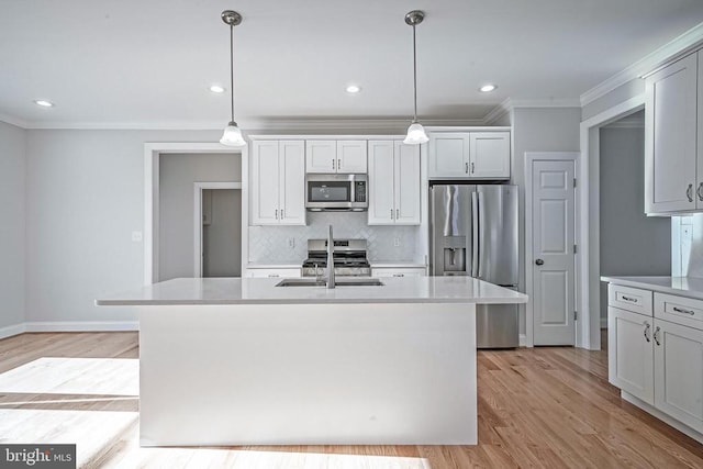 kitchen featuring a kitchen island with sink, sink, pendant lighting, and stainless steel appliances