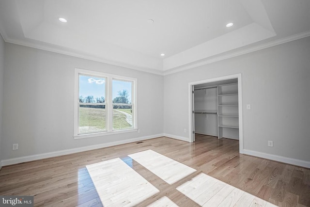 unfurnished bedroom featuring light wood-type flooring and a tray ceiling