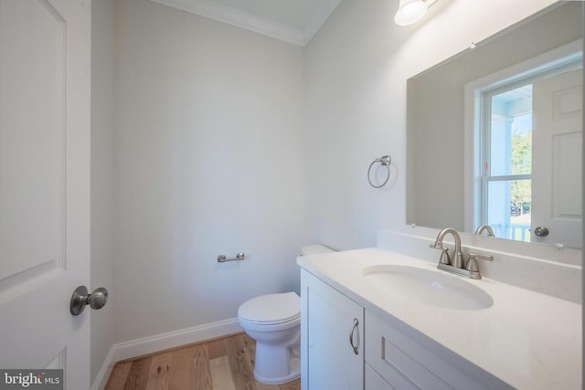 bathroom with hardwood / wood-style flooring, vanity, ornamental molding, and toilet