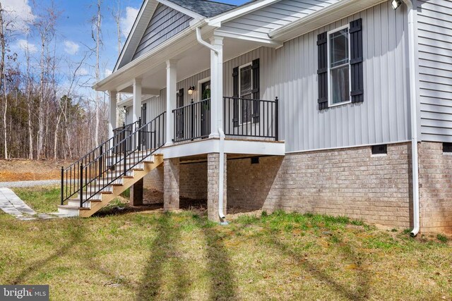 view of side of property featuring crawl space, a lawn, a porch, and stairway