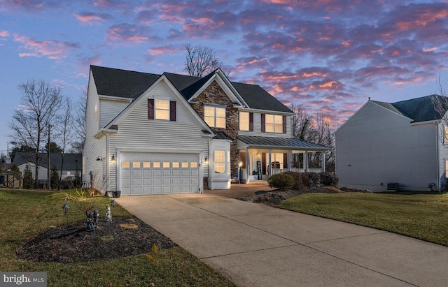 front facade with a garage, a lawn, and covered porch