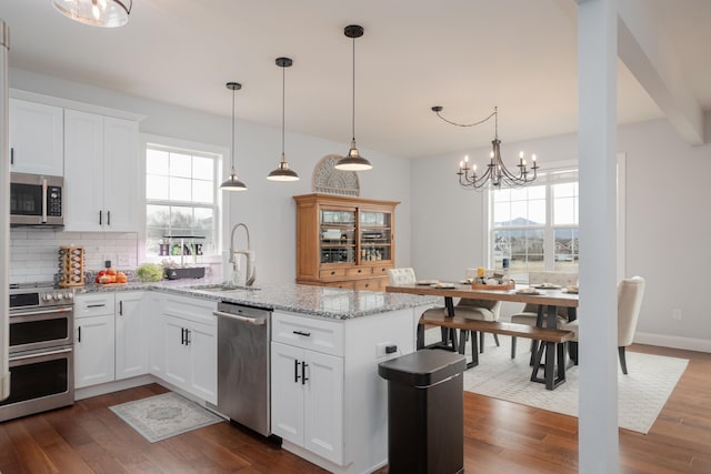 kitchen featuring a chandelier, a peninsula, stainless steel appliances, and dark wood-style flooring