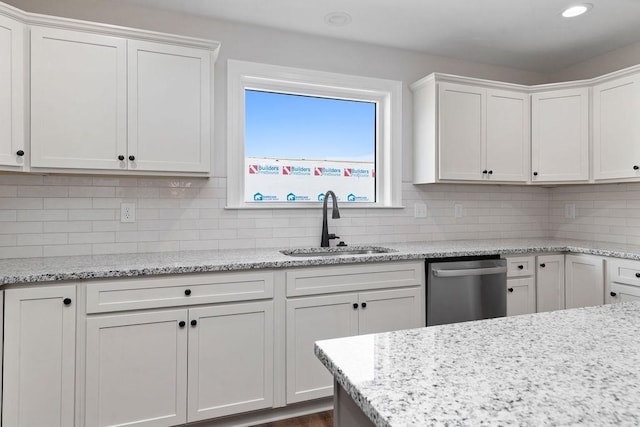 kitchen with a sink, stainless steel dishwasher, white cabinetry, and decorative backsplash