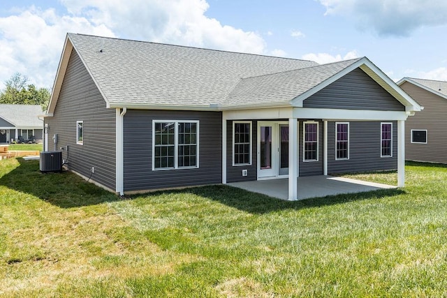 rear view of property featuring roof with shingles, a patio, cooling unit, and a lawn
