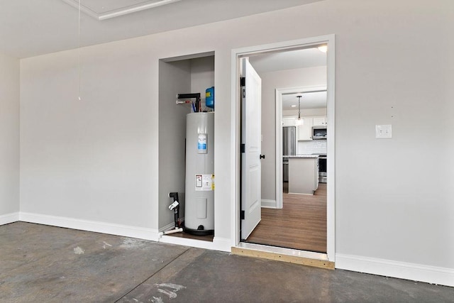 garage with baseboards, stainless steel fridge, and water heater