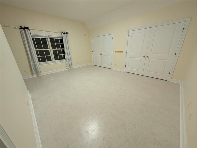 unfurnished bedroom featuring vaulted ceiling and two closets