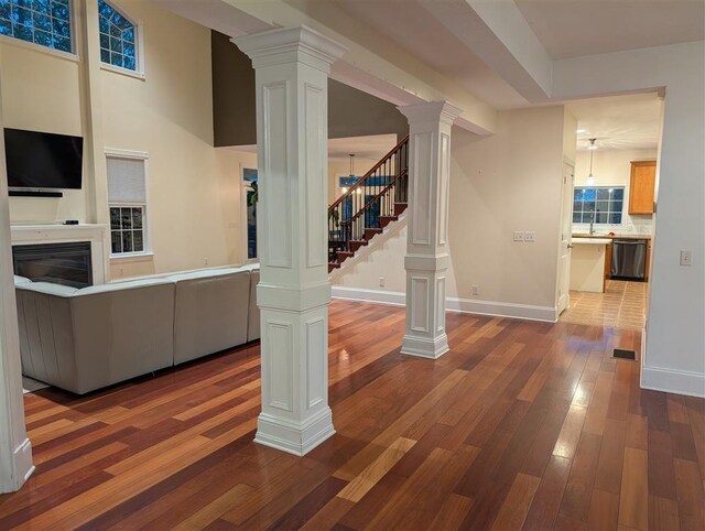 unfurnished living room featuring wood-type flooring and ornate columns