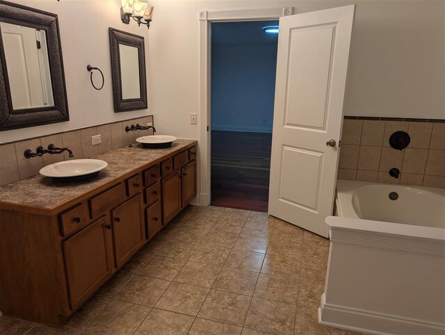 bathroom with tile patterned floors, a tub to relax in, vanity, and decorative backsplash