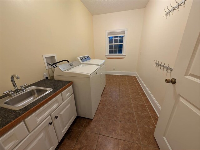 washroom with sink, cabinets, a textured ceiling, dark tile patterned flooring, and independent washer and dryer