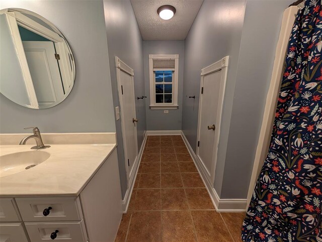 bathroom with tile patterned flooring, vanity, and a textured ceiling