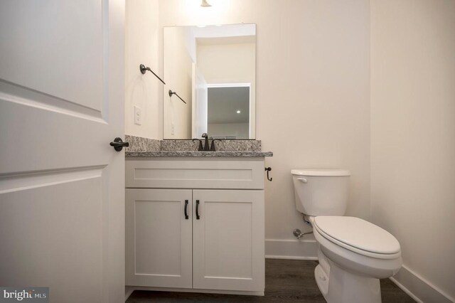 bathroom with hardwood / wood-style flooring, vanity, and toilet