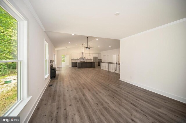 unfurnished living room with dark hardwood / wood-style flooring, crown molding, vaulted ceiling, and a wealth of natural light