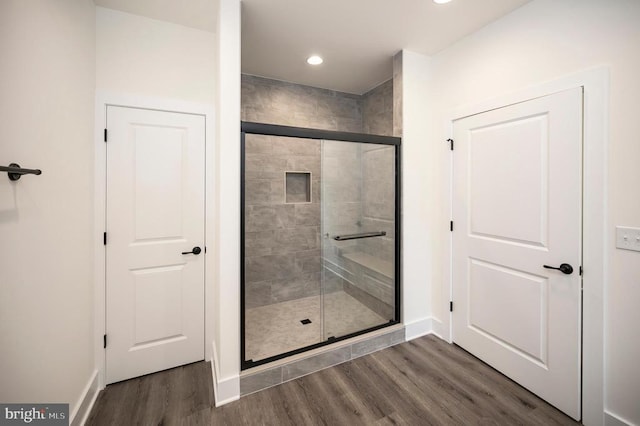 bathroom with hardwood / wood-style flooring and a shower with door