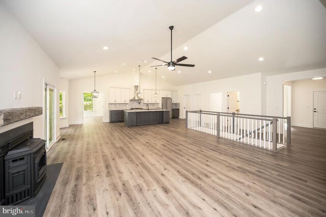 unfurnished living room with sink, hardwood / wood-style flooring, high vaulted ceiling, and ceiling fan