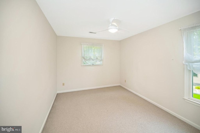 empty room featuring light carpet, plenty of natural light, visible vents, and baseboards