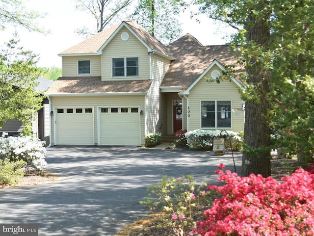 view of front of house with driveway, a shingled roof, and an attached garage