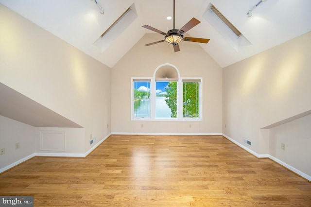 additional living space with a skylight, light wood finished floors, visible vents, baseboards, and a ceiling fan