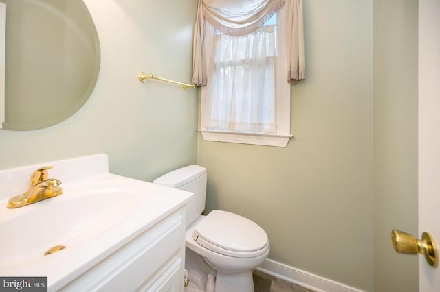 bathroom with toilet, baseboards, and vanity