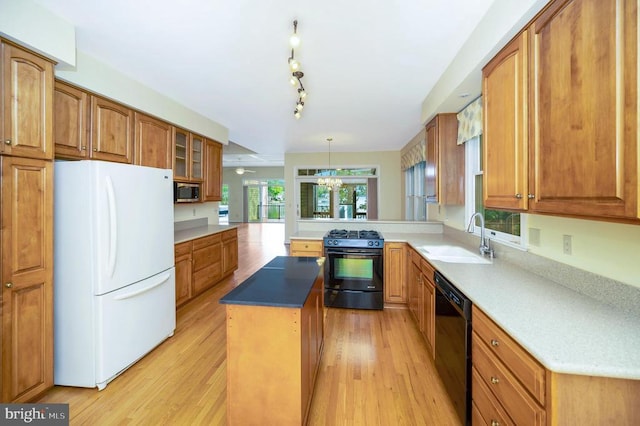 kitchen featuring a sink, light wood-style floors, a center island, black appliances, and brown cabinetry