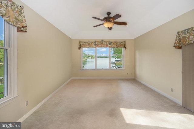 spare room featuring a tray ceiling, light carpet, ceiling fan, and baseboards