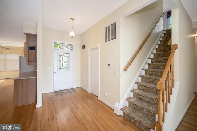 entrance foyer featuring light wood finished floors, baseboards, stairs, and visible vents