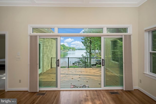 doorway to outside featuring a water view, wood finished floors, visible vents, baseboards, and crown molding